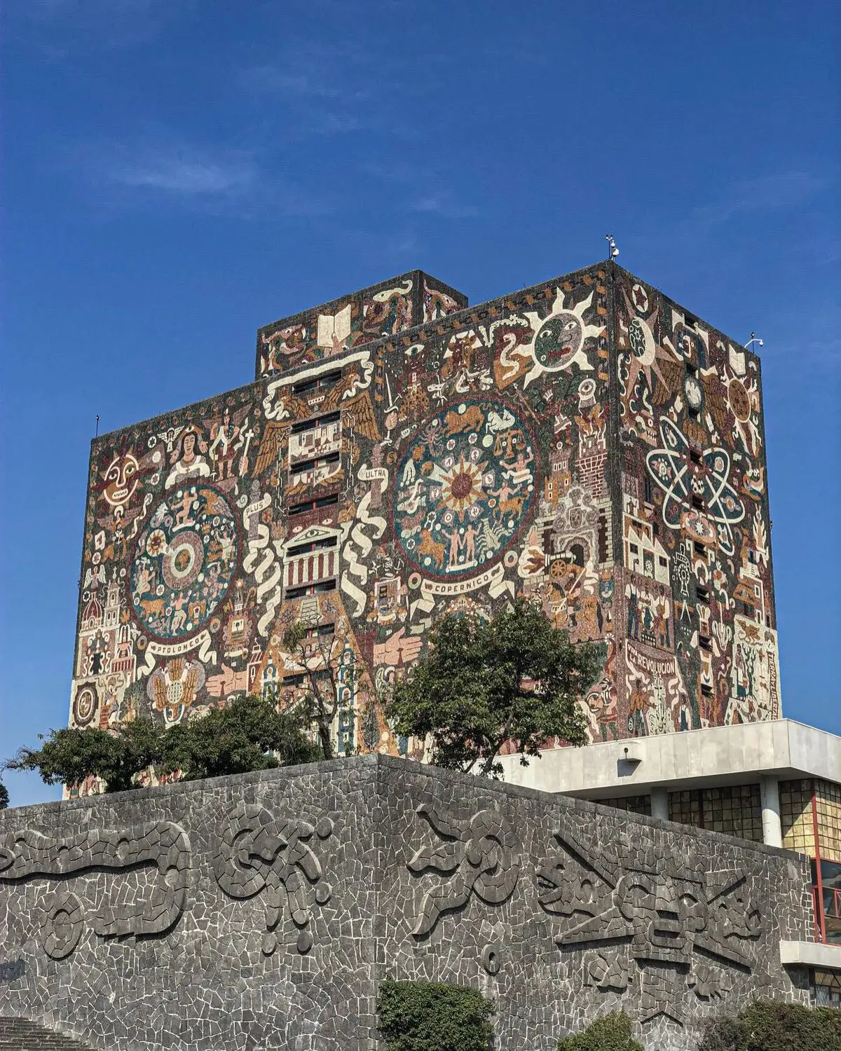 نمای ساختمان‌های بتنی به سبک بروتالیسم در مکزیک با هندسه صلب و سایه‌های عمیق که نشان‌دهنده ترکیب معماری مدرن و سنتی است.