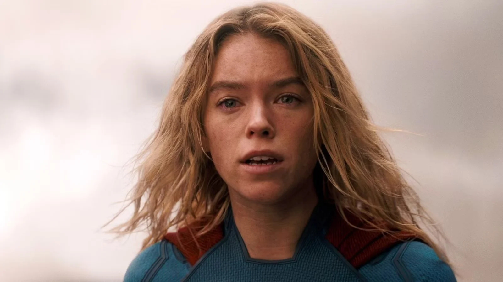 Close up of a Blonde Woman in a Blue Superhero Suit with a Red Cape Looking Worried